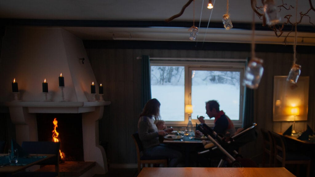 Koselig middag ved peisen i vinterlig landskap, med tente lys og familie ved bordet.
