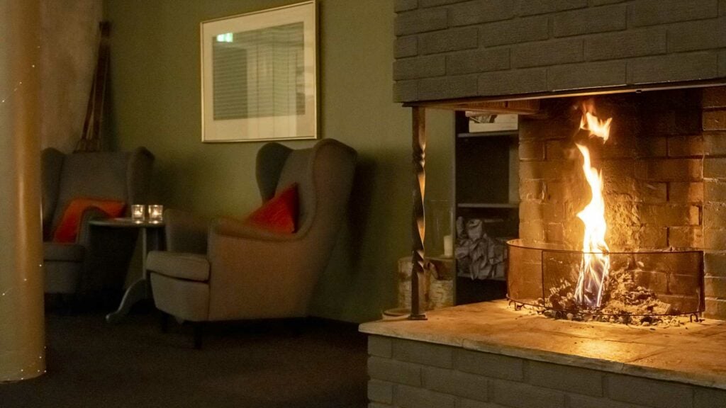 Koselig stue med lenestoler og levende peis for en avslappende atmosfære.