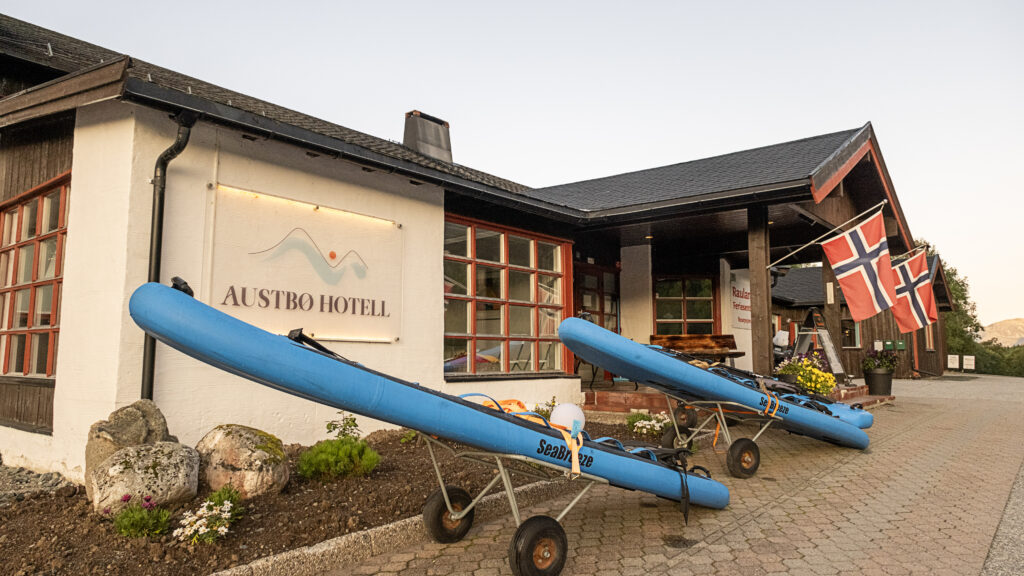 Austbø Hotell inngang med kajakker og norske flagg, som gir en tradisjonell og aktiv ferieopplevelse.