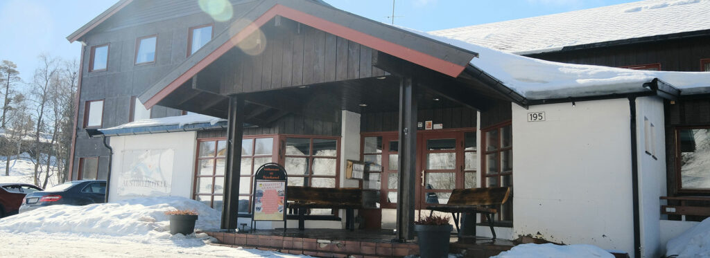 Vinterutsikt av inngangsparti til Austbø Hotell i snødekte omgivelser.