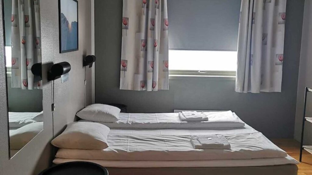 Moderne hotellrom med dobbelseng, speil og naturlig lys fra vinduet. En perfekt overnatting i byen.