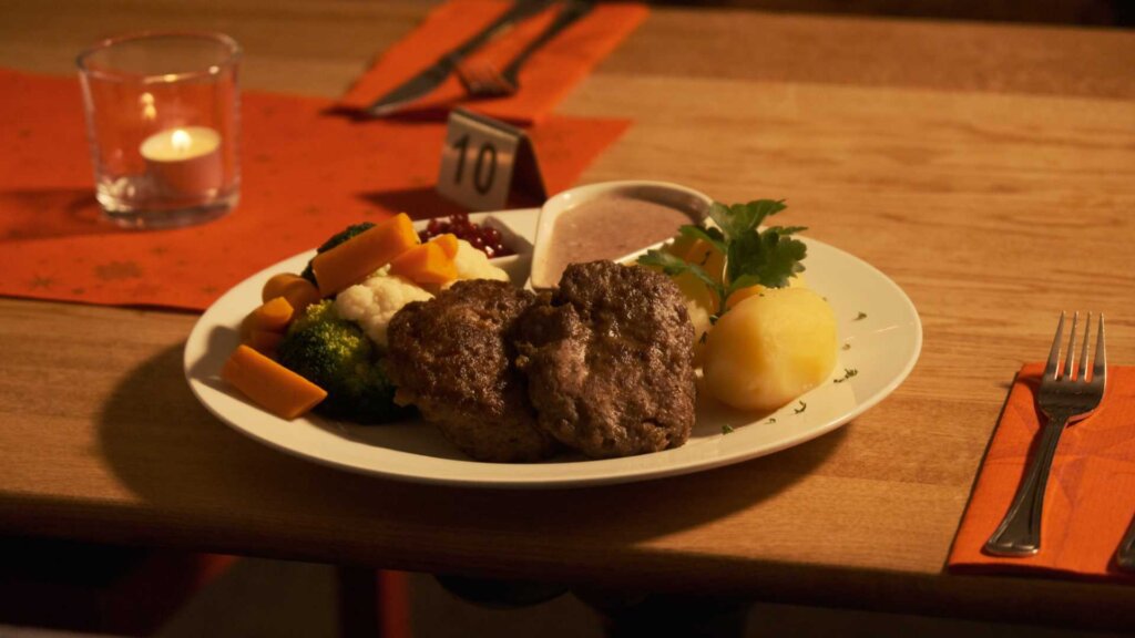 Tradisjonell norsk middag med kjøttkaker, grønnsaker, poteter og brun saus på en tallerken.
