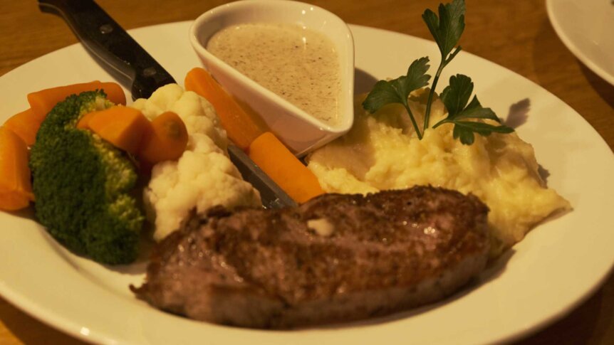 Biffmiddag med potetmos, grønnsaker og saus på tallerken, pyntet med persille.