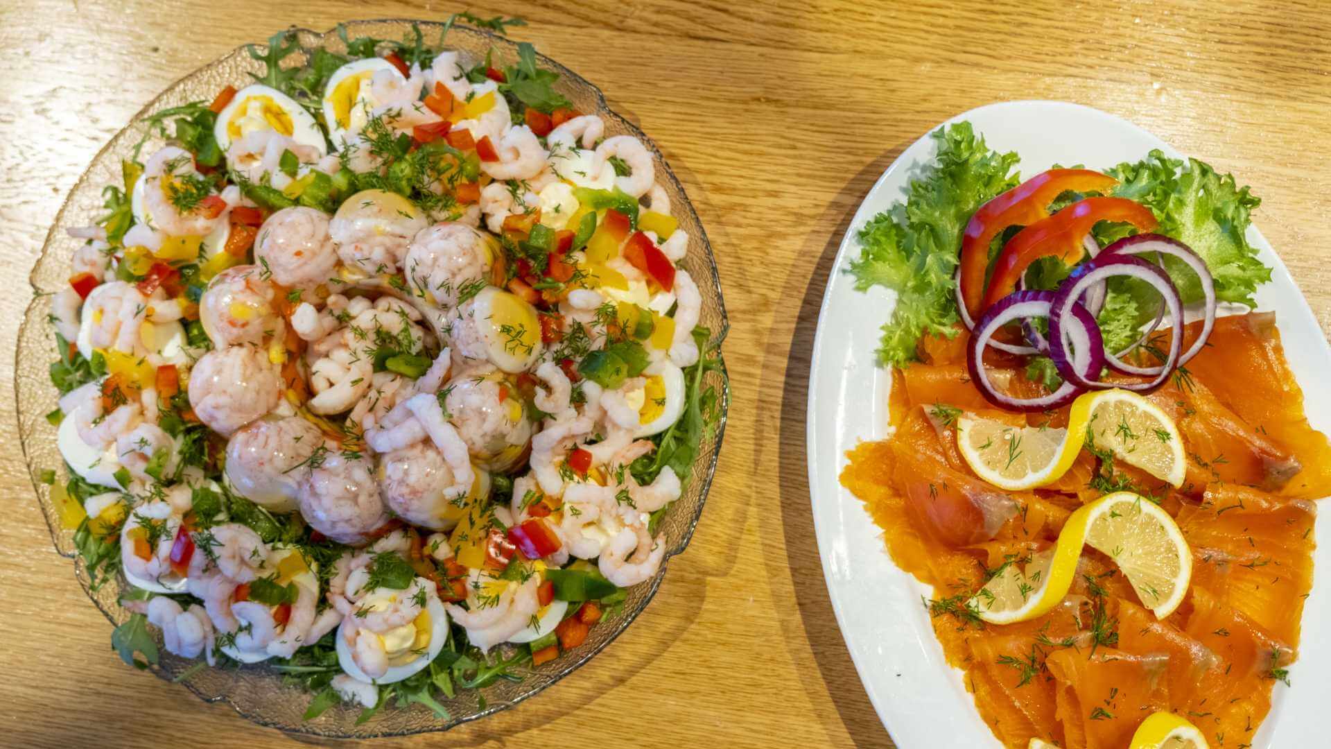 Fersk sjømat med reker, røkelaks, sitron, salat og grønnsaker servert på fat idealisert for norsk matglede.