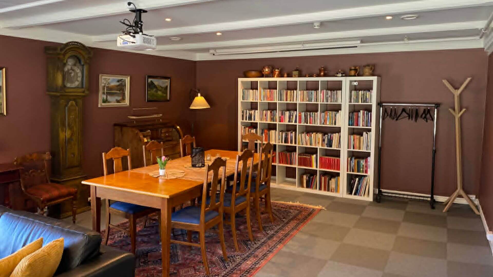 Lys, koselig rom med spisebord, bokhylle og vintage møbler, perfekt for møter og sosiale sammenkomster.