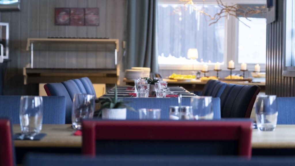 Koselig restaurant med pent dekkede bord, vakkert interiør og stemningsfull belysning.