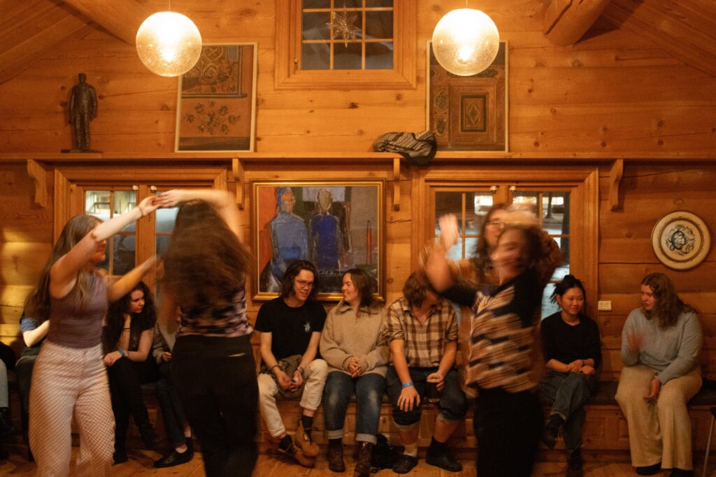 Ungdommer danser og har det moro i en koselig, trehustradisjonell hytte med kunst på veggene.