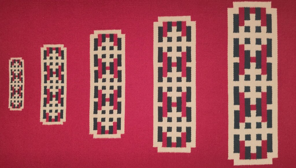 Mønster av geometriske figurer i rødt, svart og beige på en vevet bakgrunn. Kunstnerisk tradisjonelt design.