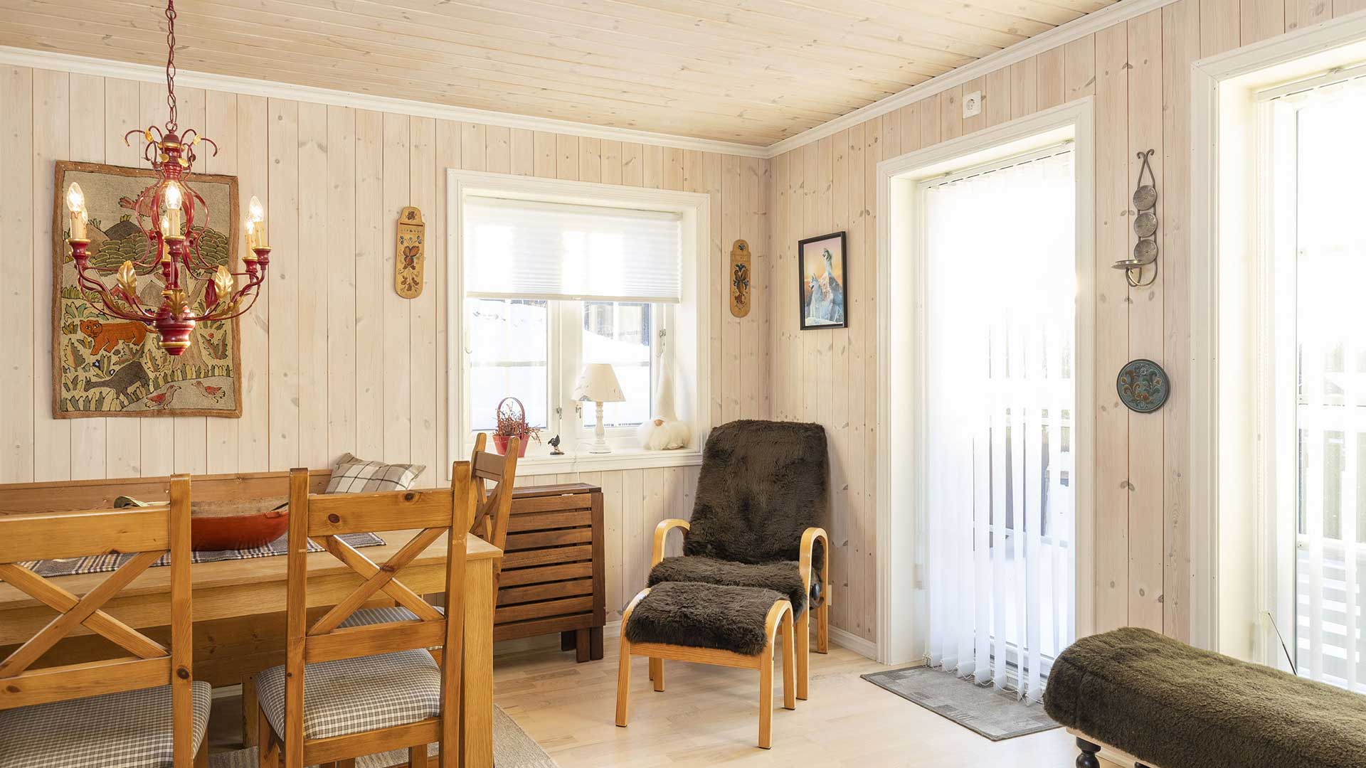 Koselig stue med trepanel, spisestue i tre og rød lysekrone i rustikk stil. Veggkunst til dekorasjon.