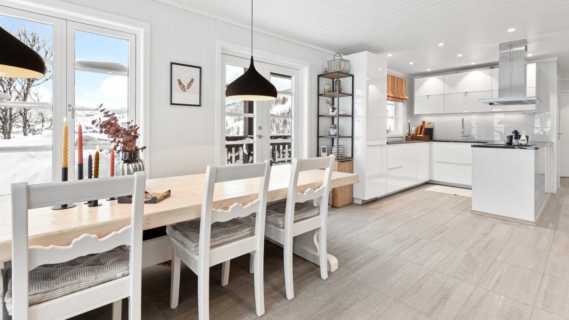 Lyst og moderne kjøkken med spisebord, store vinduer og vinterutsikt. Skandinavisk design.