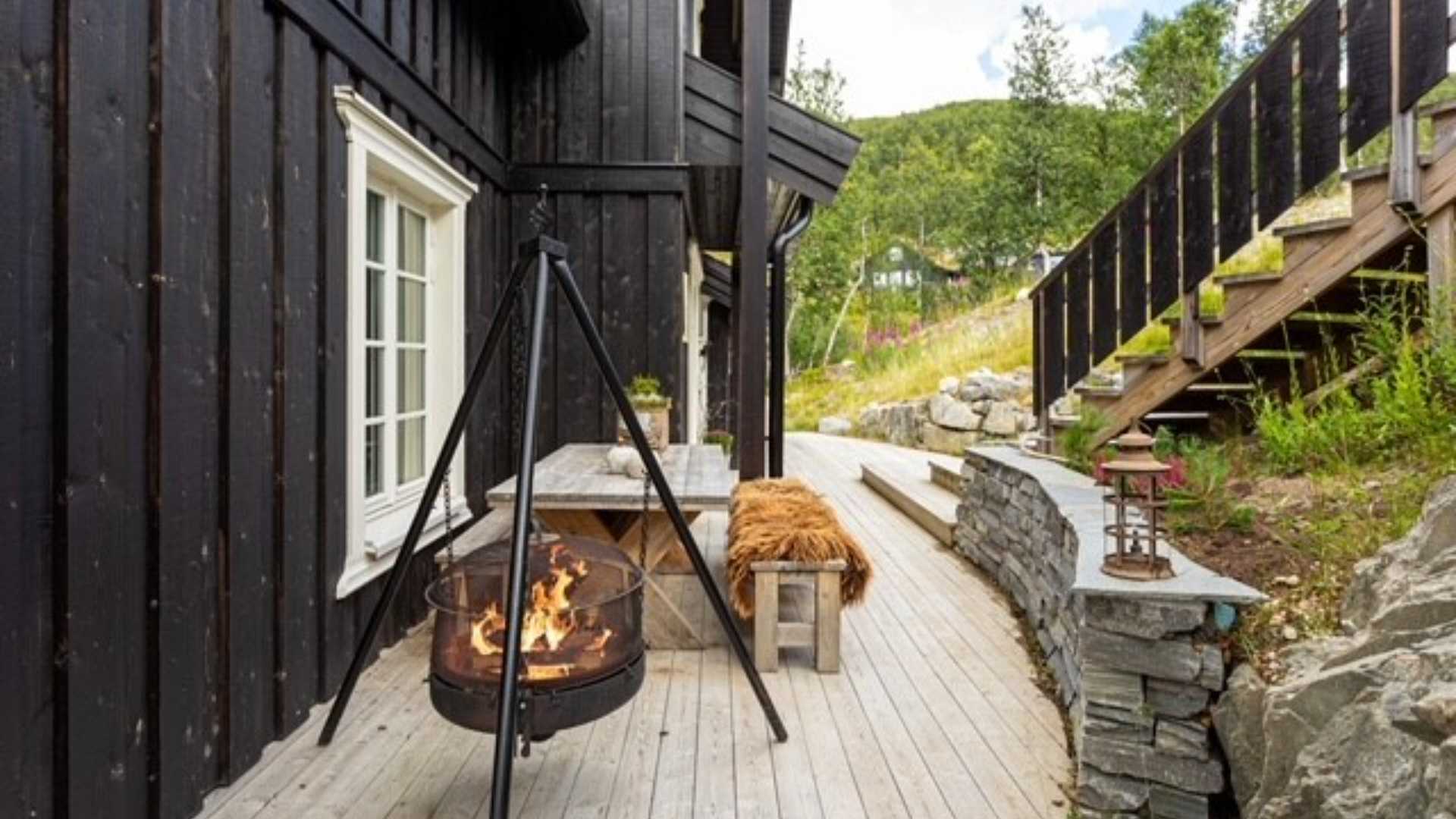 Koselig terrasse med peis, trebenk og utsikt mot hage. Perfekt for avslapning i idylliske omgivelser.