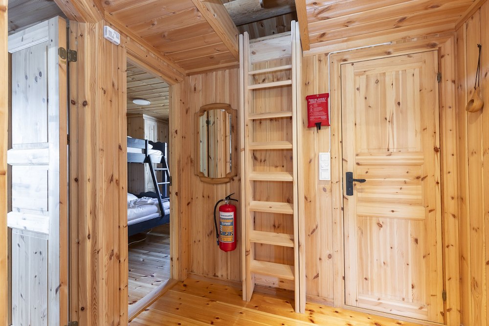 Koselig hytteinteriør med trevegger, stige og køyesenger. Harmonisk og funksjonell design for fjellopplevelser.