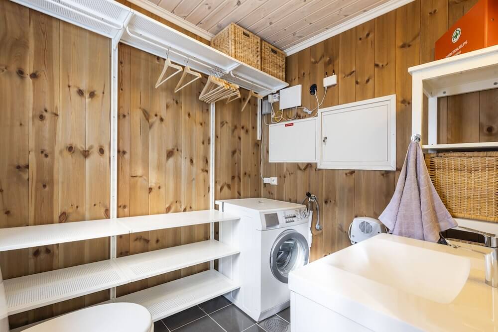 Lyst vaskerom med tremøbler, vaskemaskin og oppbevaring. Stilig og funksjonell innredning for moderne hjem.