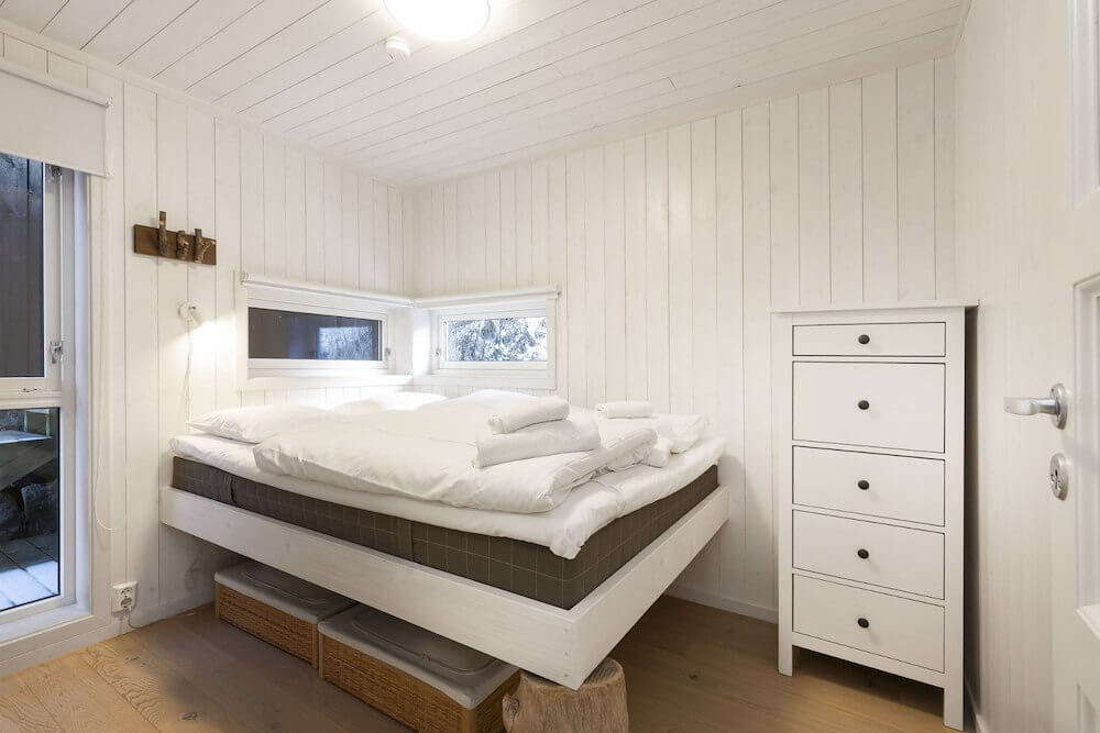 Lyst og koselig soverom med dobbeltseng og hvite møbler i tradisjonell norsk stil.