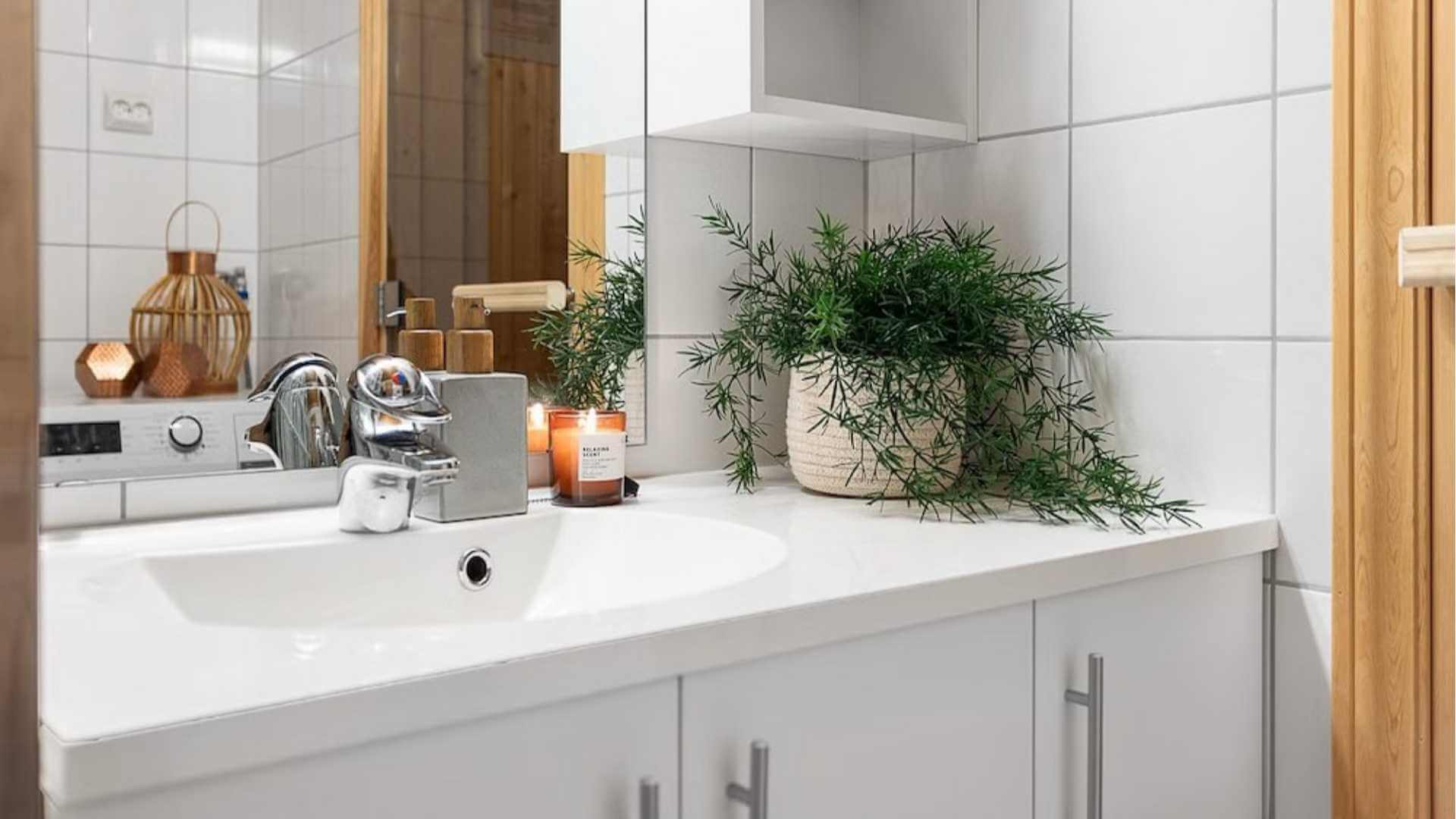 Moderne bad med vask, planter, stearinlys og stilige detaljer for en koselig atmosfære.