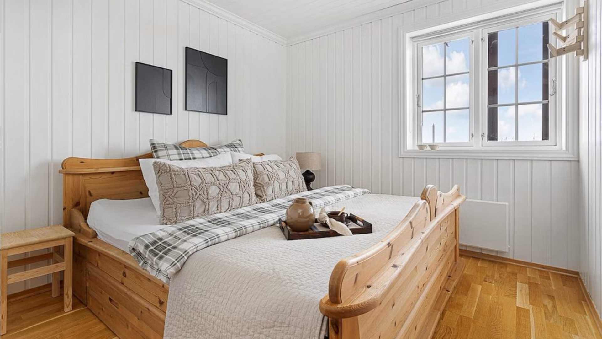 Lyst og koselig soverom med dobbeltseng, ved vinduet og stilige kunstverk på veggen.