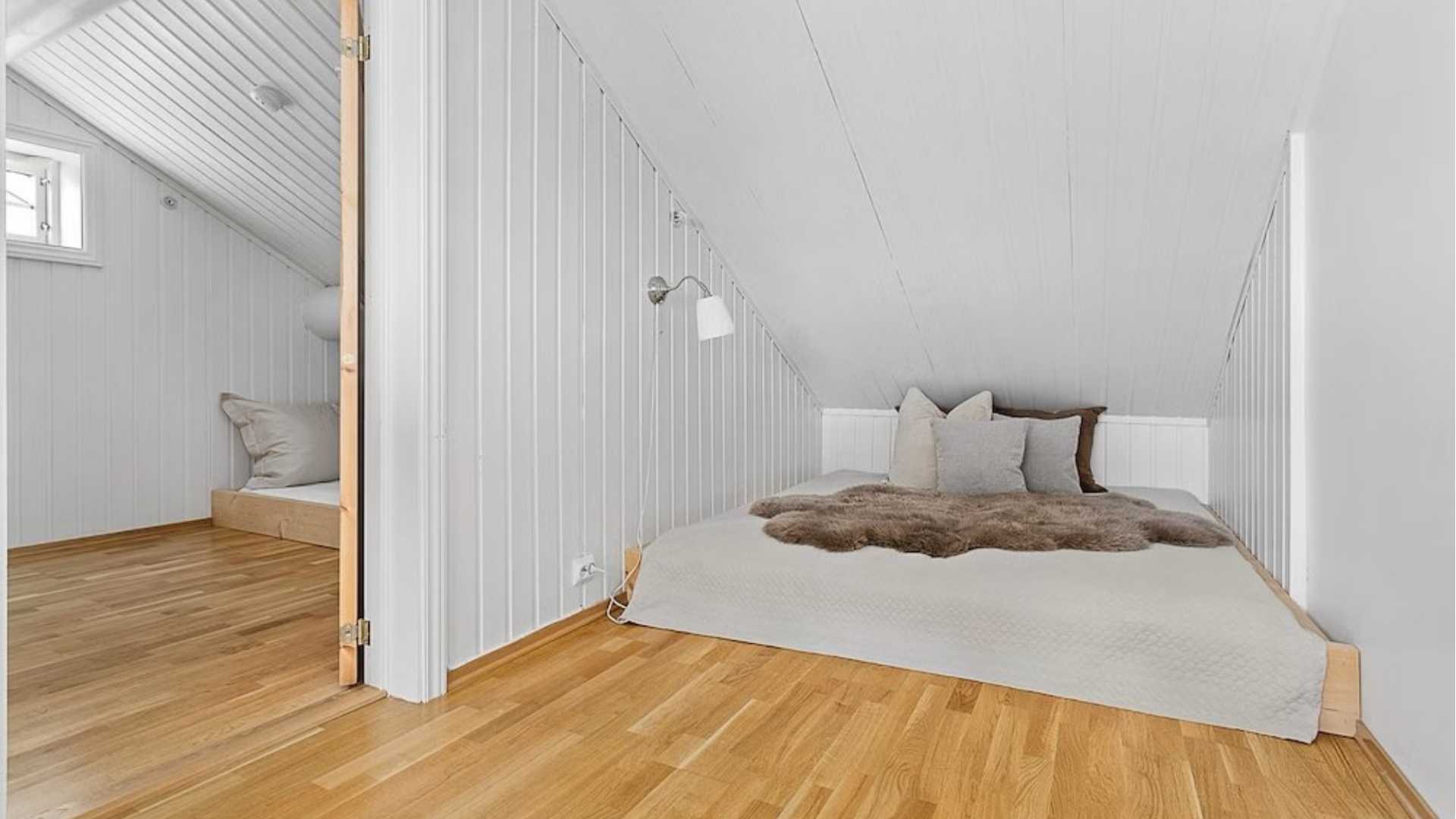 Lyst og koselig rom med skråtak, naturlig treverk og komfortable puter for avslapning. Perfekt for en rolig natt.