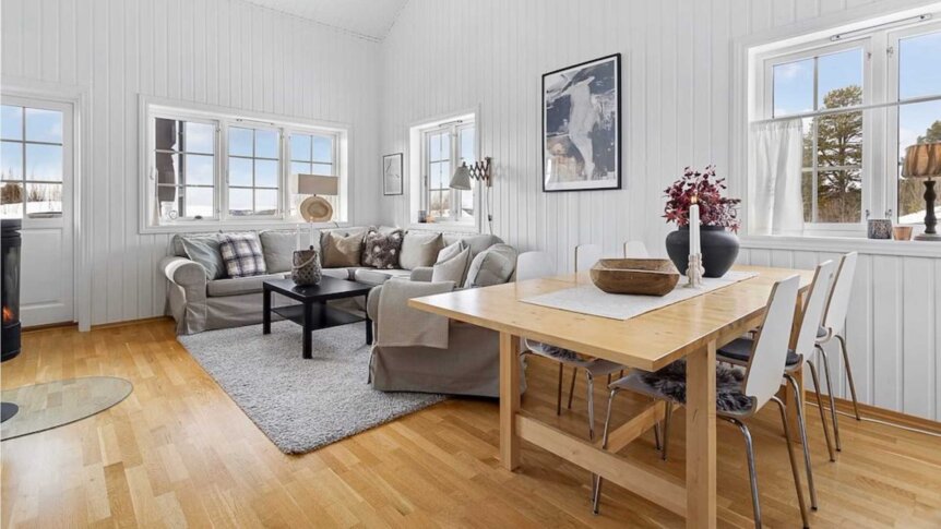 Lys og moderne stue med koselig sofa, spisebord og store vinduer som gir naturlig lys.