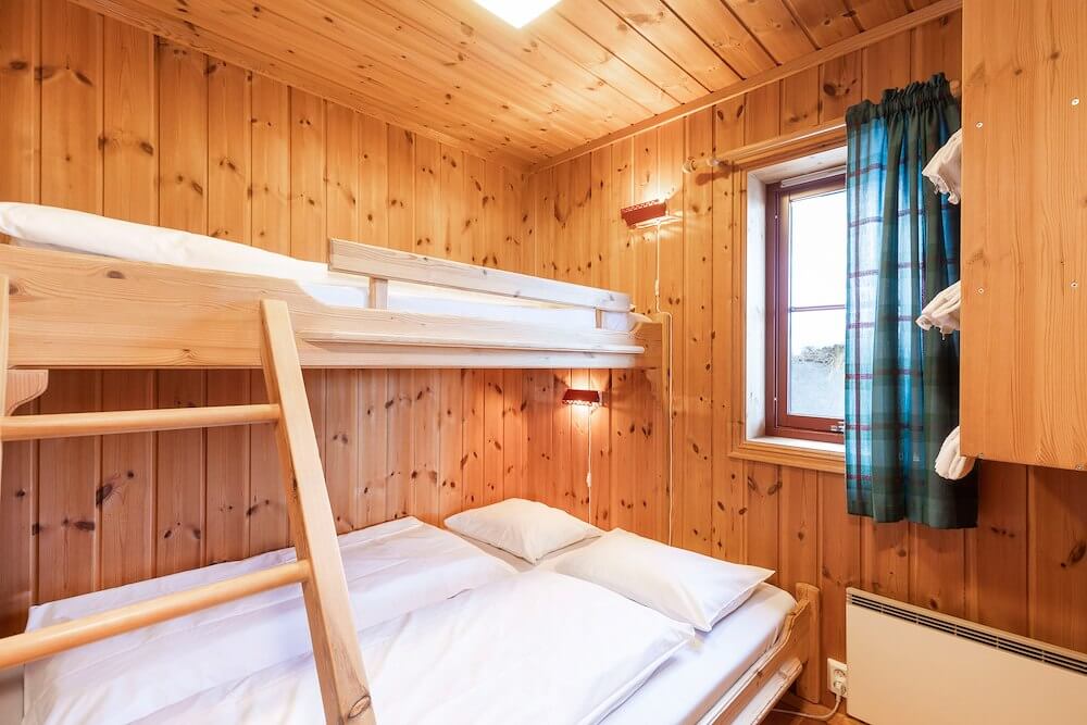 Koselig rom med trebunker, lys innredning og vindu med gardiner, perfekt for avslapning etter en dag ute.