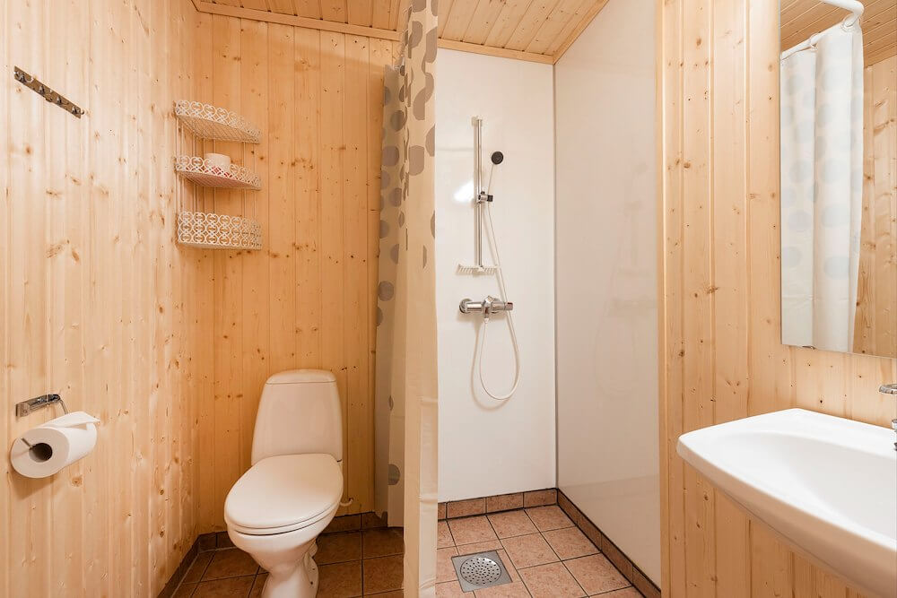 Moderne bad med dusj, toalett og vask, omkranset av lyst treverk for en koselig atmosfære.