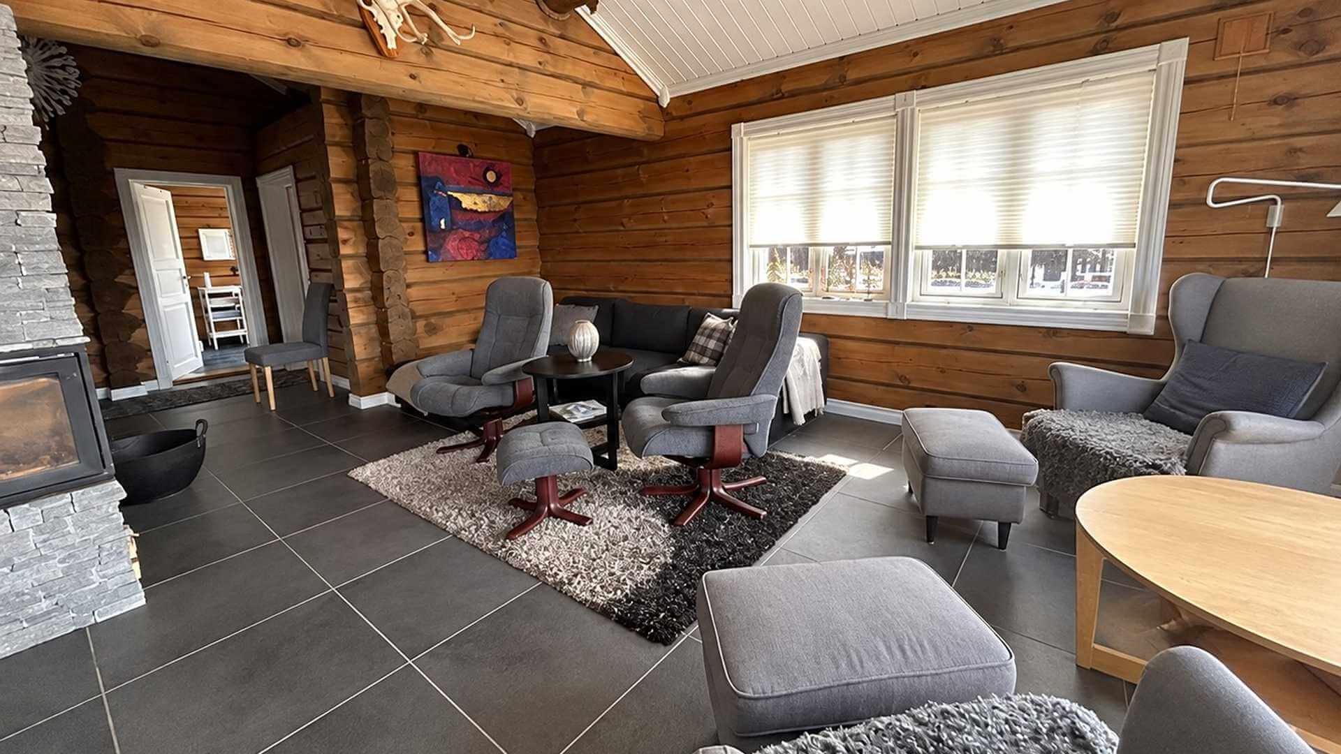 Koselig stue med moderne møbler, peis og tregulv i en hytte, perfekt for avslapning.