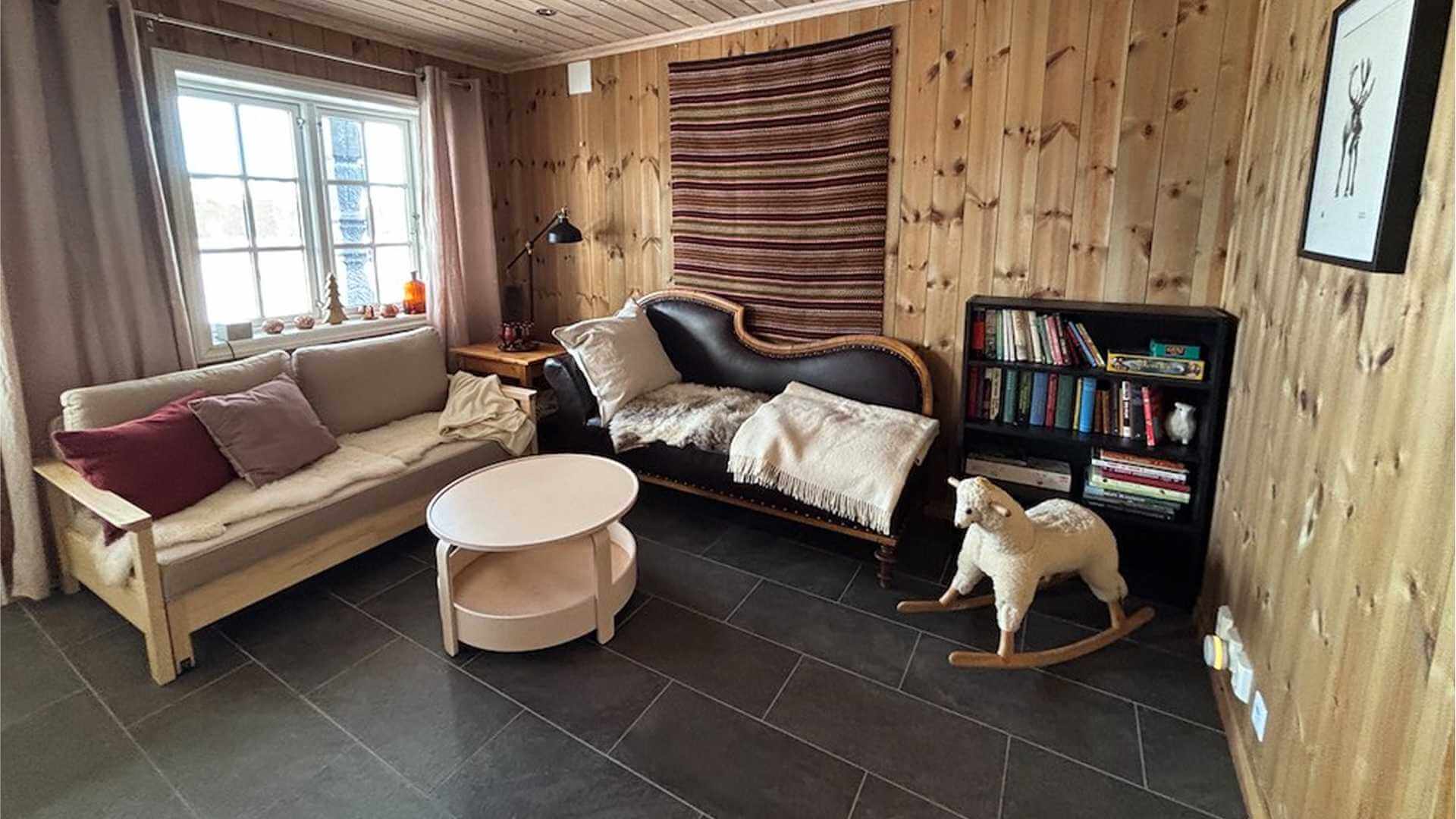 Koselig stue med trevegg, sofagruppe, bøker og en leke. Perfekt for avslapning og hygge hjemme.