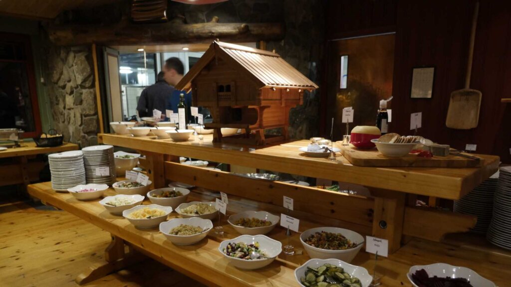 Buffébord med trehusdekorasjon og et utvalg av salater og retter i en koselig, tradisjonell restaurant.