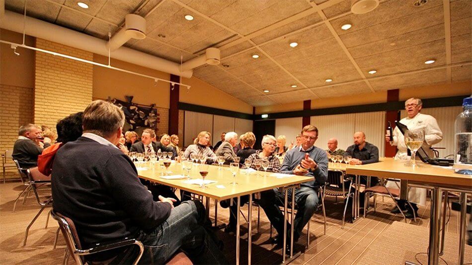 Vinsmaking med entusiastisk gruppe mennesker som deltar i en smakfull opplevelse i et moderne konferanserom.