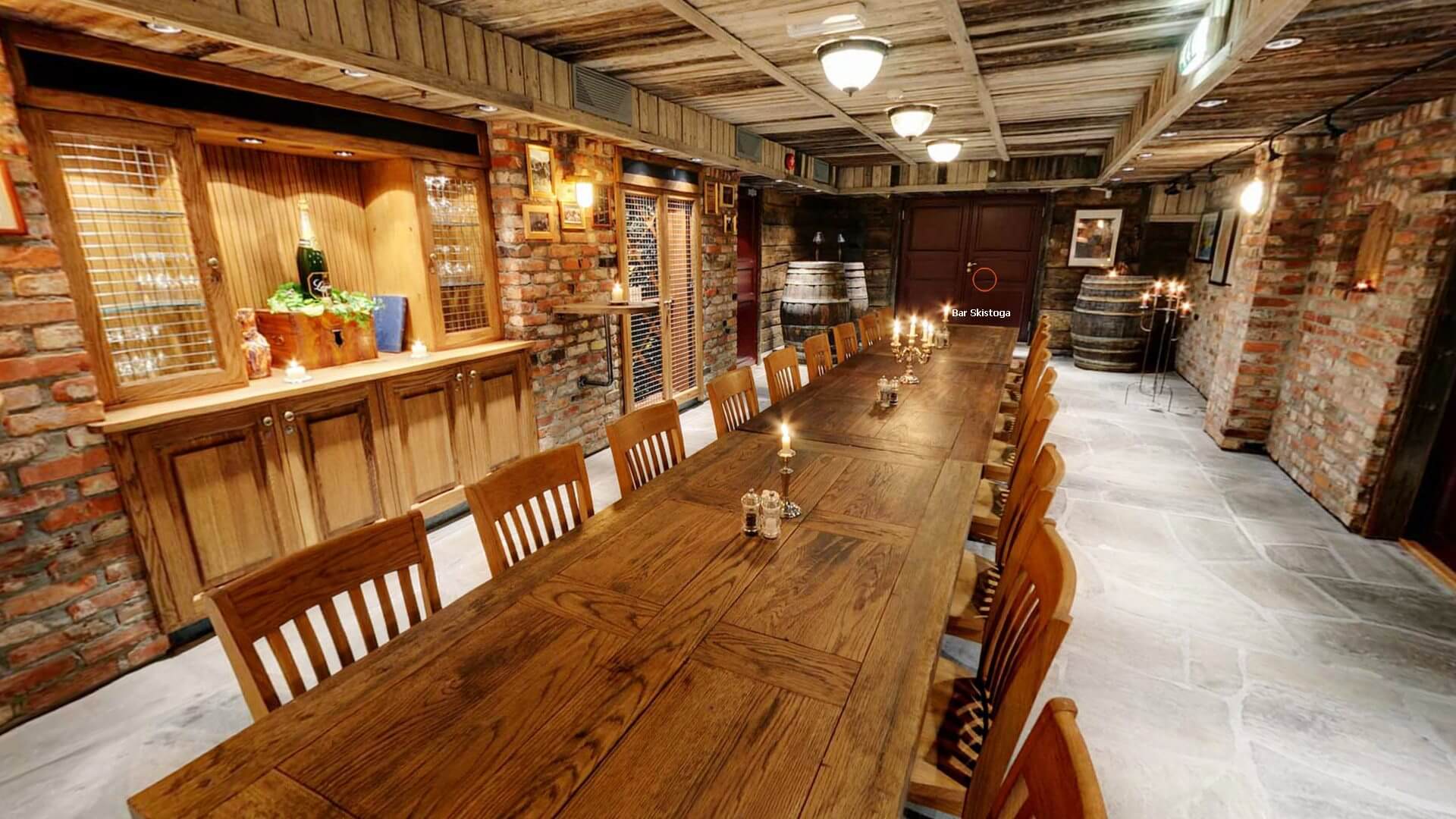 Rustikk vinkjeller med lang trebord, tønner, murvegger og dempet belysning, klar for intim sammenkomst.