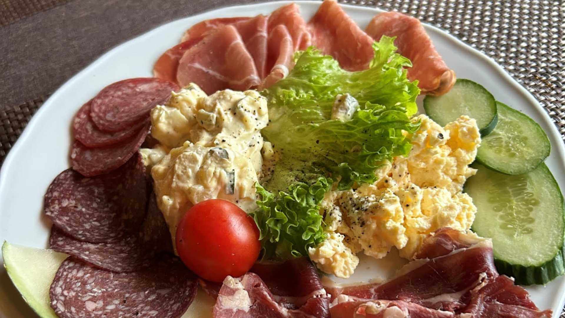 En smakfull tallerken med salami, skinke, eggesalat, agurk, salat og cherrytomat. Perfekt til frokost eller lunsj.