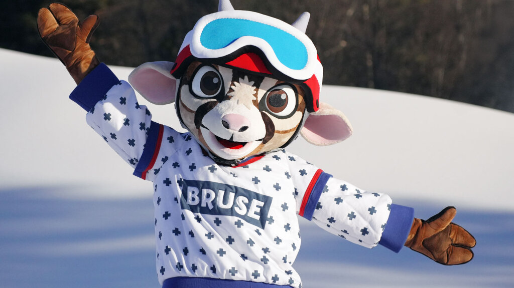 Maskot i vintertøy med Bruse på genseren i snølandskap.