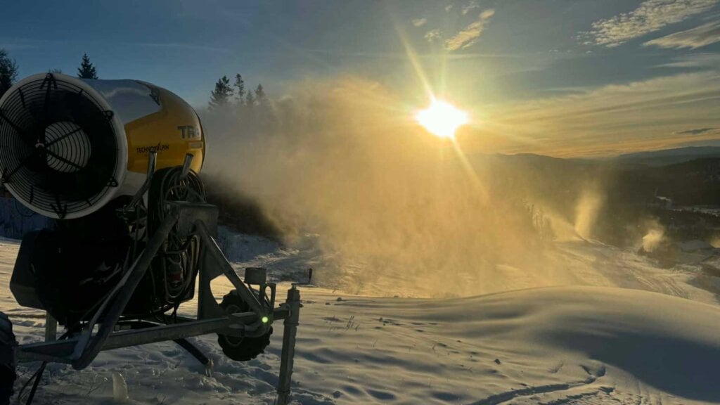 Snøkanon i solnedgang: Kunstig snødekke skapes i naturskjønne omgivelser. Vinterstemning på fjellet.
