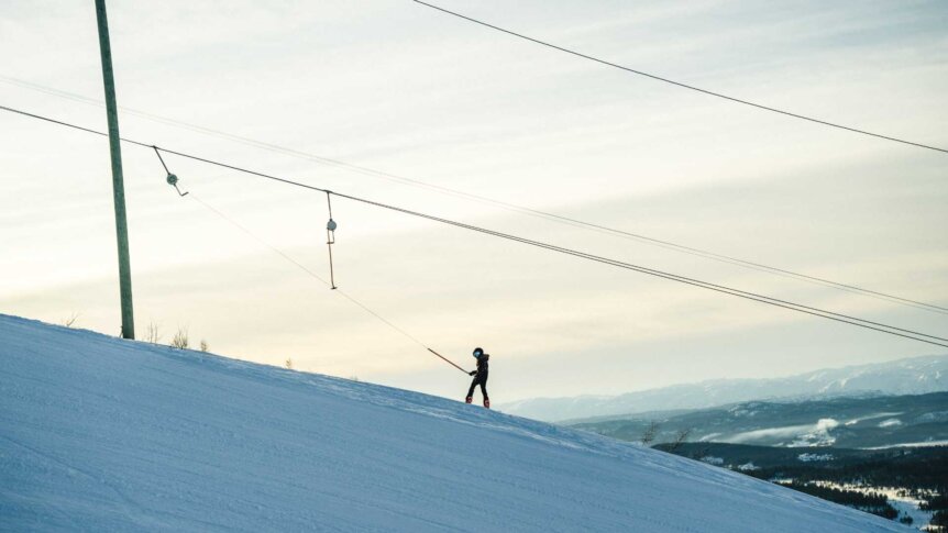 Ungdom på ski stiger oppover en bakke med skitrekk i vinterlandskapet. Klare dager og snødekte fjell.