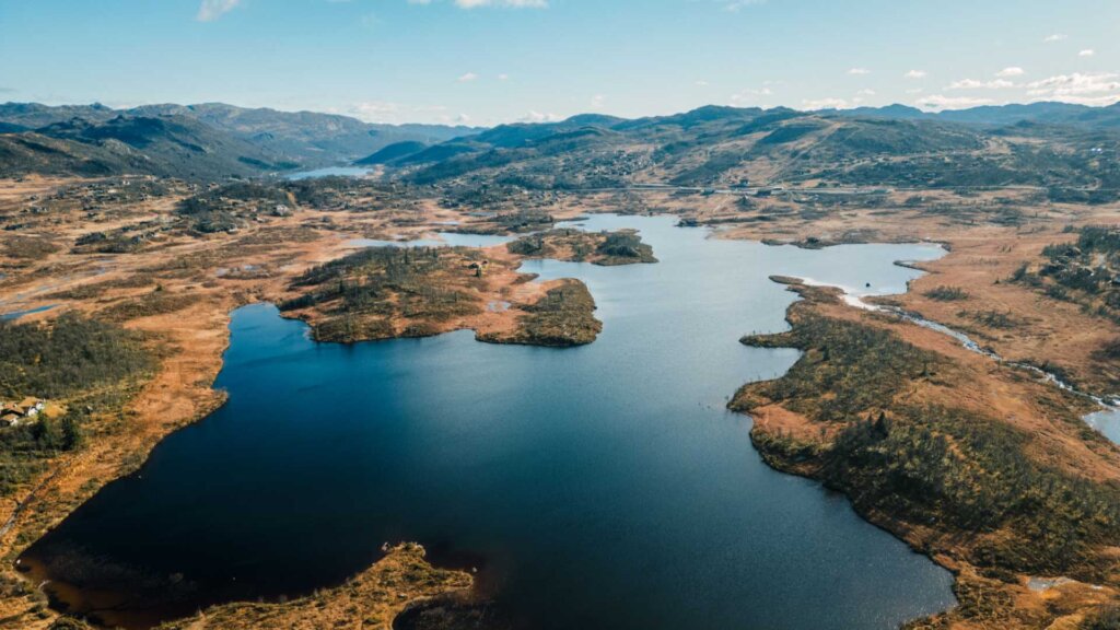 Utsikt over innsjøer og fjell i norsk natur, med tørre områder og grønne partier i horisonten.