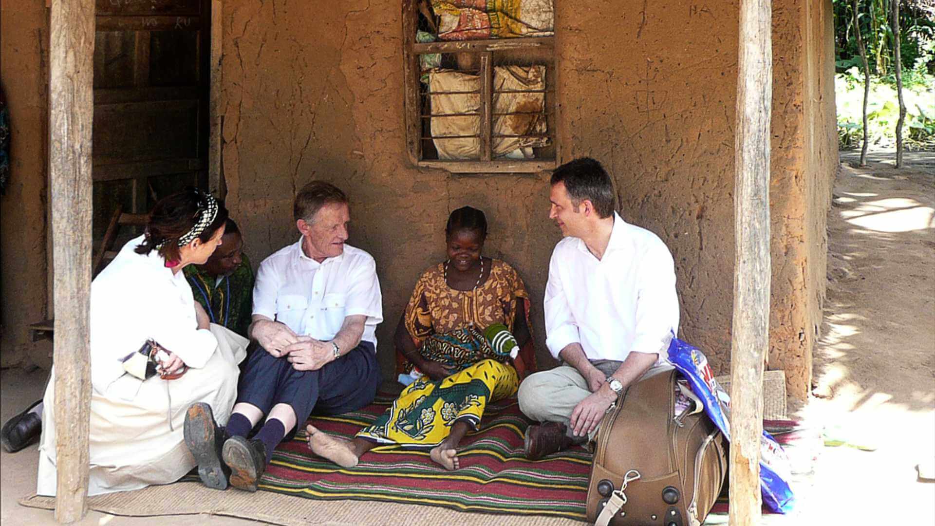 Møte mellom mennesker i tradisjonell setting, samtaler på en teppe i en landsby.