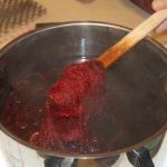 Rødbeter kokes i en gryte, damp stiger opp, rødbetene røres med en tresleiv.