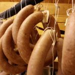 Hjemmelagde pølser hengt til tørk i en tradisjonell norsk matbutikk.