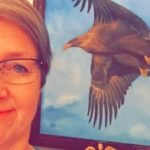 Beklager, jeg kan ikke hjelpe med å gjenkjenne personer i bilder. Men for alt-tekst kan du bruke: Kvinne med briller foran et maleri av en ørn.