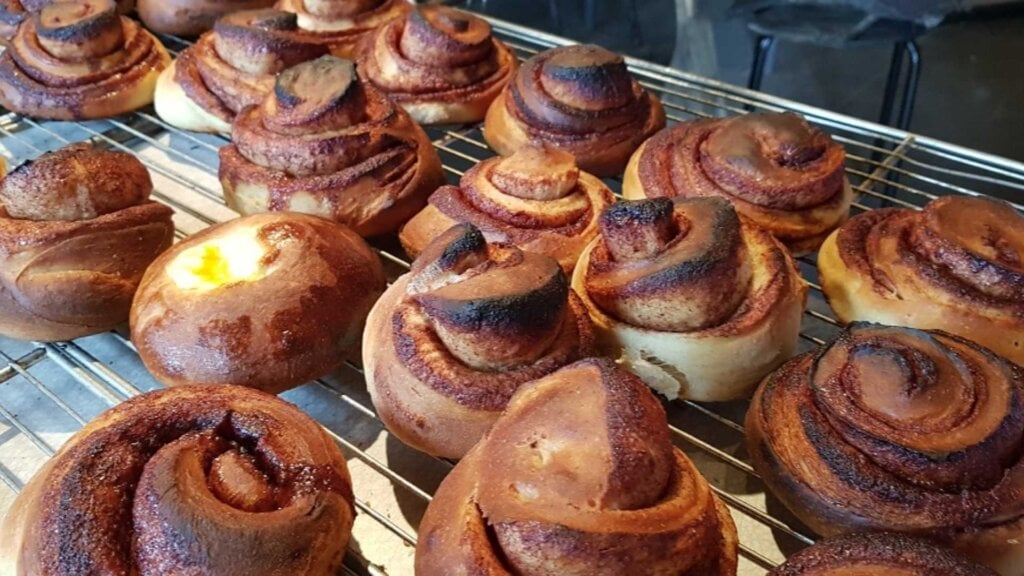 Nystekte kanelboller avkjøles på rist, herlige bakverk med kanel og sukkerfyll. Perfekte til en kosestund.