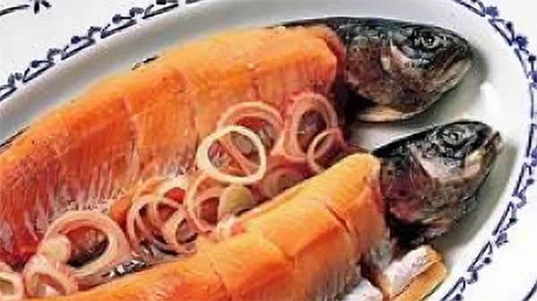 To skiver gravlaks med løk på et dekorativt fat, en norsk delikatesse.