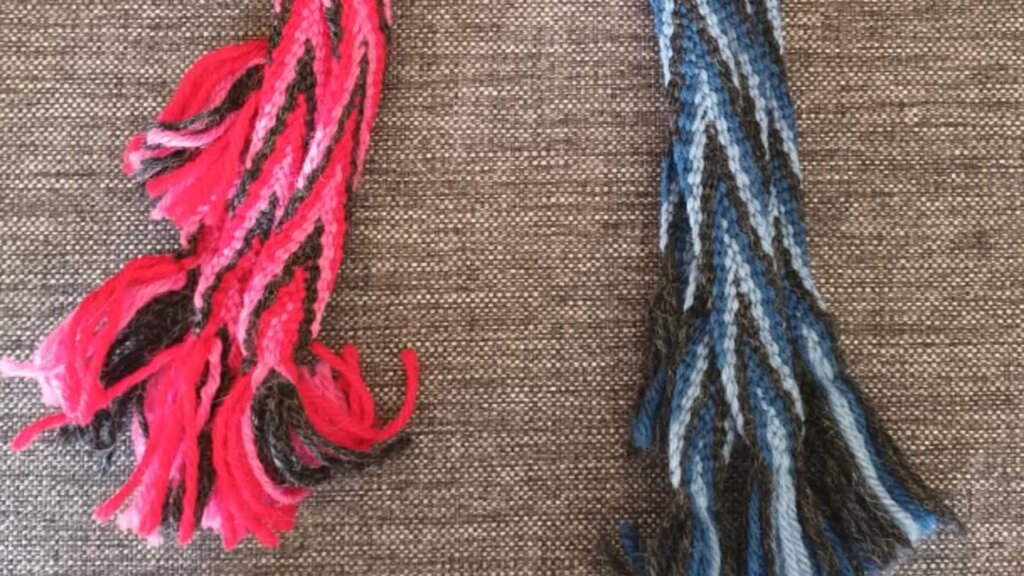 Rosa og blå strikkede dusker på brun bakgrunn, fargerik tekstur av håndlaget garn.