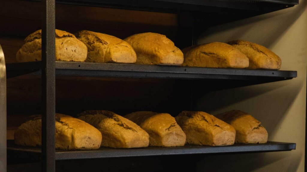Friskbakte brød på hyller i et bakeri, klare til å nytes av kunder. Aromatisk og delikat bakst.