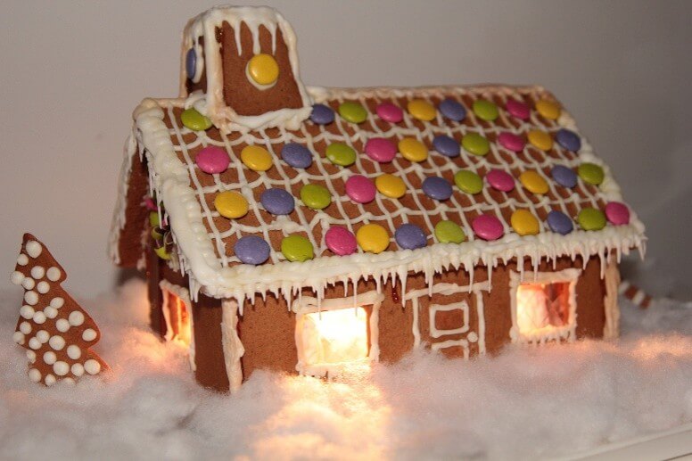 Pepperkakehus med fargerike godterier og snø, som lyser opp i vintermørket. Perfekt for juledekorasjon.