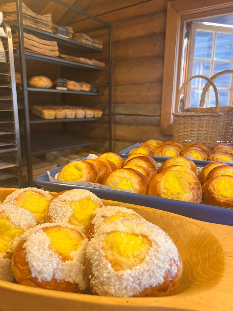 Fristende bakverk med kokos og krem i en koselig bakeributikk. Nybakte brød i bakgrunnen.