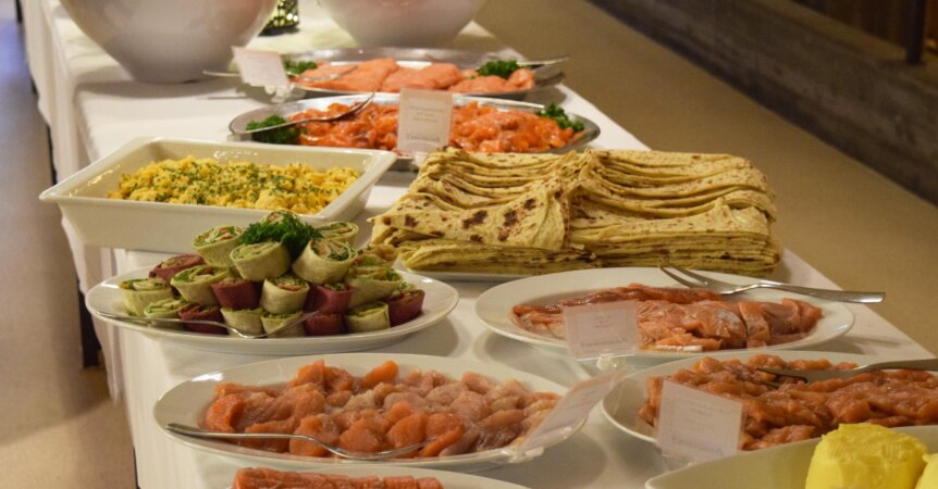 Smørbrødbuffet med laks, wraps, potetsalat og lefser på et festbord. Delikate retter til arrangementer.