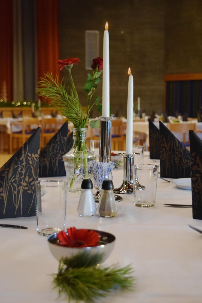 Dekorert middagsbord med stearinlys, blomster og servietter i en koselig restaurantsetting.