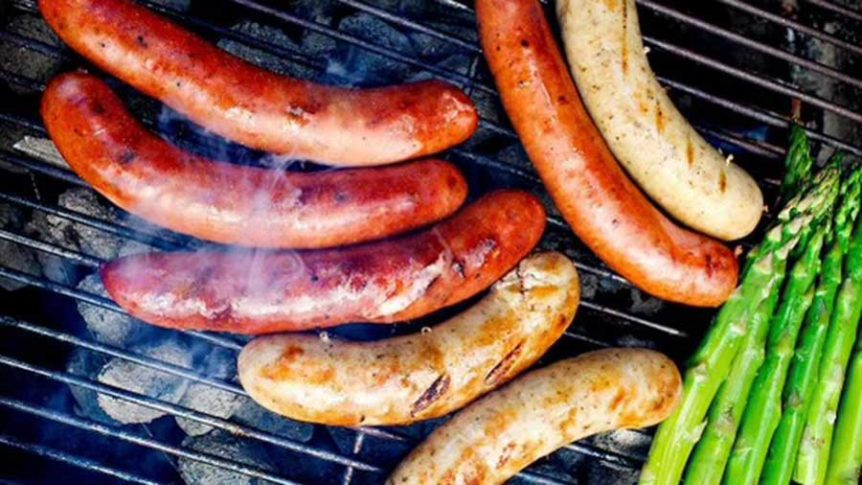 Grillet pølse og asparges på kullgrill. Perfekt for sommermat og utendørs grilling.