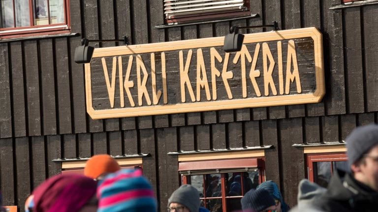 Bygning med skiltet Verli Kafeteria og mennesker i vinterklær foran.