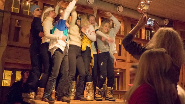 Gruppe ungdommer danser og har det gøy på en festkveld i en trehytte, mens en person tar bilde.