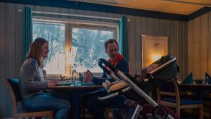 Familie spiser middag på restaurant med utsikt over snødekt landskap gjennom vinduet.